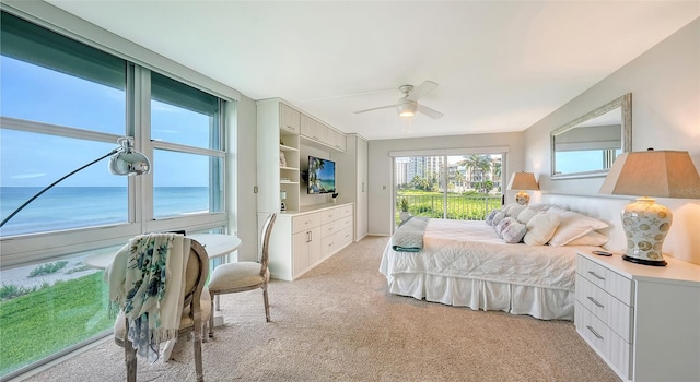 bedroom featuring a water view, light colored carpet, and ceiling fan