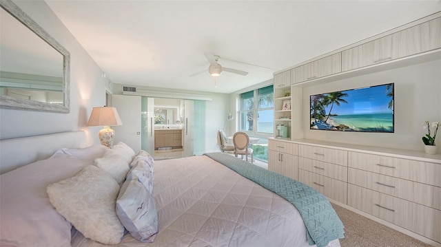 bedroom with light carpet, connected bathroom, and ceiling fan