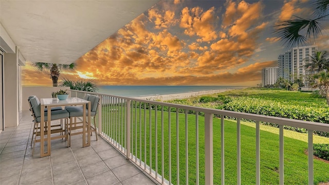 balcony at dusk featuring a water view