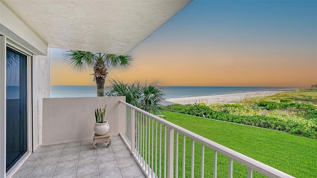 balcony at dusk with a view of the beach and a water view