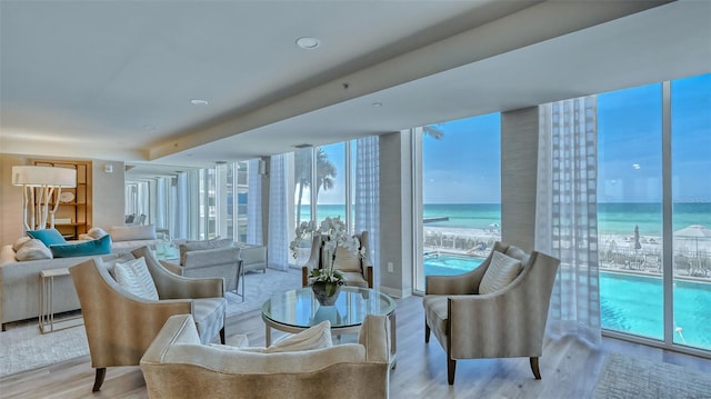 living room with light hardwood / wood-style floors, a water view, and expansive windows