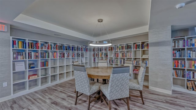 dining area featuring light hardwood / wood-style flooring and a raised ceiling