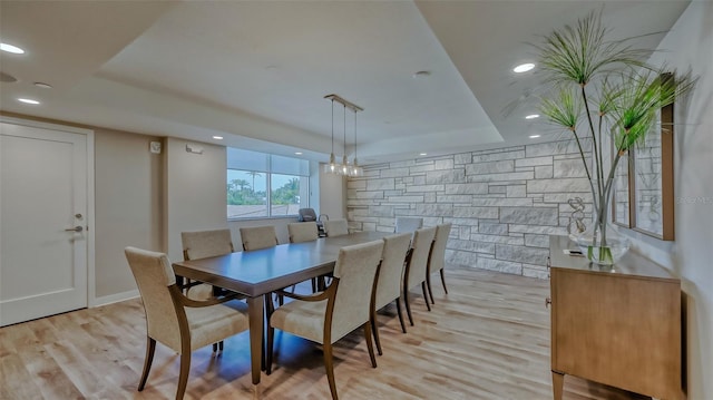 dining space with light hardwood / wood-style flooring, a chandelier, and a tray ceiling