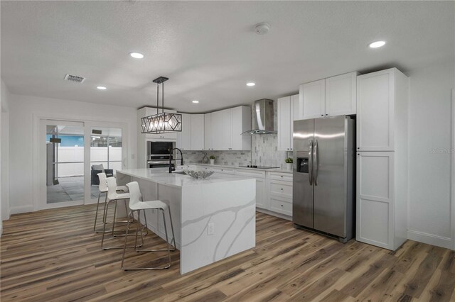 kitchen with appliances with stainless steel finishes, dark hardwood / wood-style flooring, white cabinetry, and wall chimney range hood