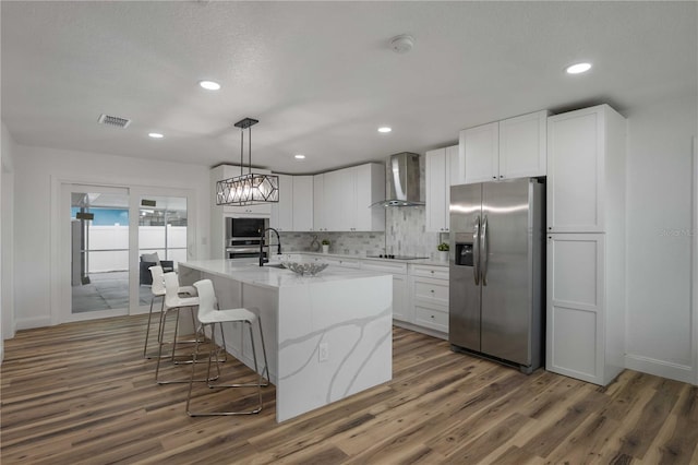 353 Suwanee Ave, Sarasota, FL 34243 - kitchen with stainless steel fridge with ice dispenser, wall chimney exhaust hood, wood finished floors, black electric stovetop, and visible vents