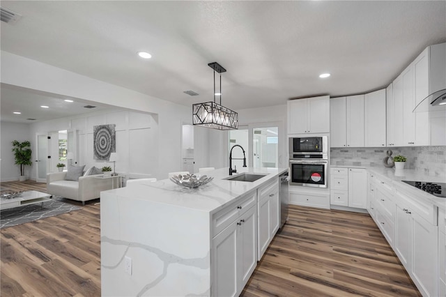 kitchen with sink, dark hardwood / wood-style flooring, white cabinetry, and a center island with sink