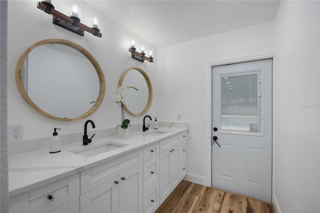 353 Suwanee Ave, Sarasota, FL 34243 - bathroom featuring double vanity, a sink, a textured ceiling, and wood finished floors