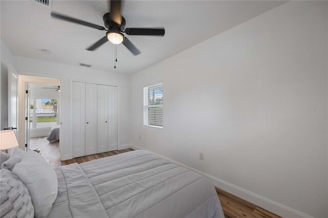 bedroom featuring multiple windows, a closet, light wood-type flooring, and ceiling fan