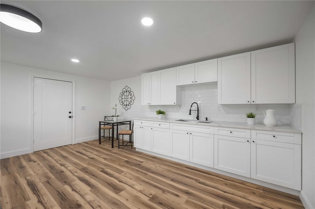 353 Suwanee Ave, Sarasota, FL 34243 - kitchen with light countertops, backsplash, a sink, light wood finished floors, and white cabinetry