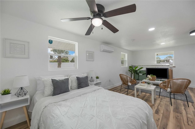 bedroom featuring a wall mounted AC, multiple windows, ceiling fan, and hardwood / wood-style floors