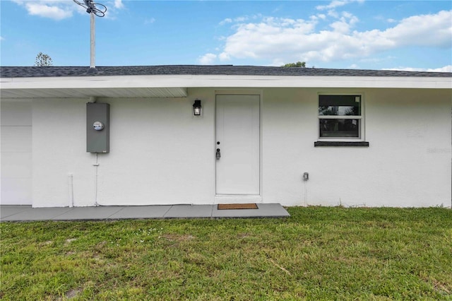 353 Suwanee Ave, Sarasota, FL 34243 - property entrance with a lawn, roof with shingles, and stucco siding