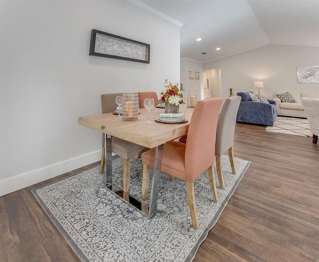 dining space featuring wood-type flooring, ornamental molding, and vaulted ceiling