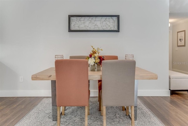 dining room with hardwood / wood-style flooring and crown molding