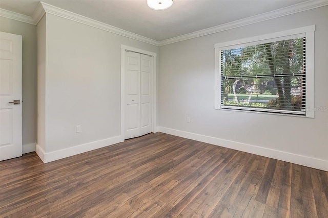 unfurnished bedroom featuring dark wood-type flooring, ornamental molding, and a closet