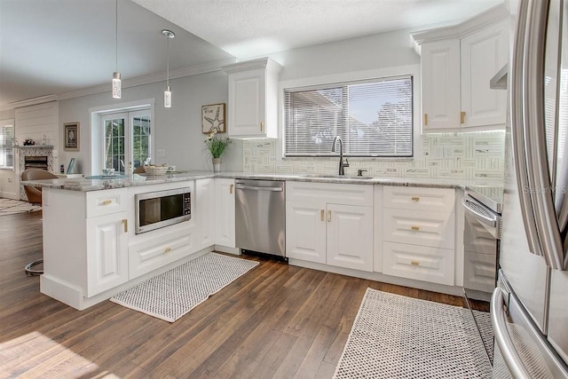 kitchen featuring sink, appliances with stainless steel finishes, light stone counters, white cabinets, and kitchen peninsula