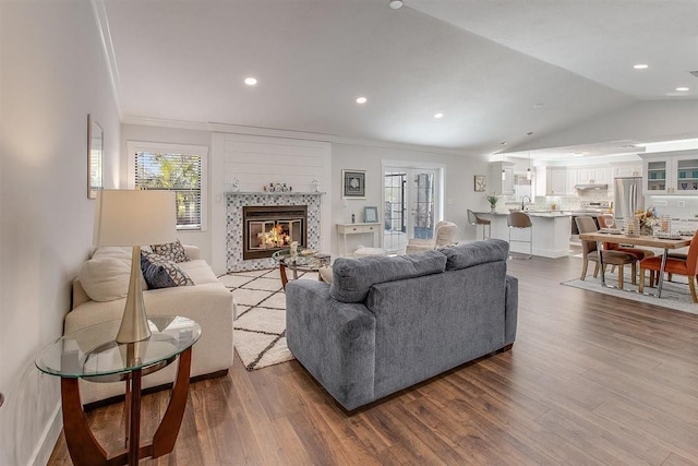 living room featuring wood-type flooring, vaulted ceiling, sink, and ornamental molding