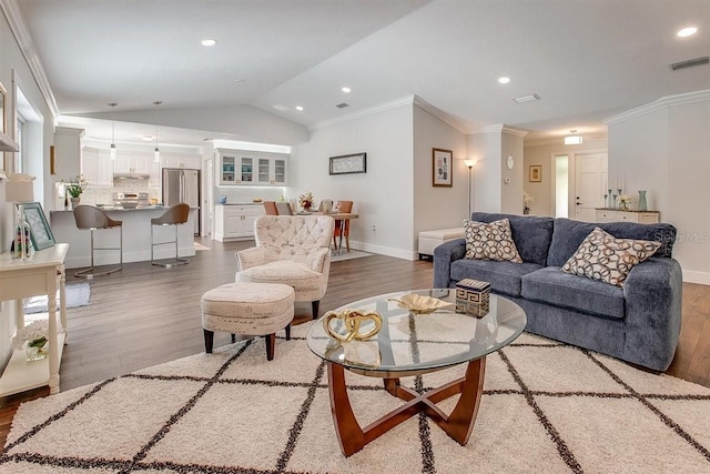 living room featuring hardwood / wood-style floors, vaulted ceiling, and ornamental molding