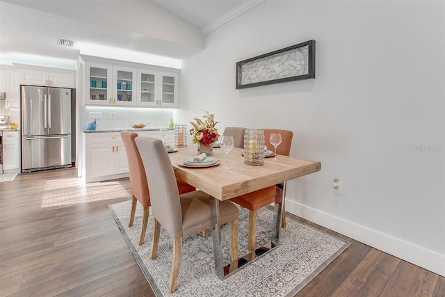 dining area featuring vaulted ceiling, ornamental molding, and light hardwood / wood-style floors