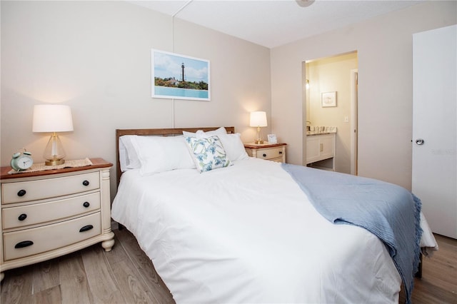 bedroom with ensuite bath and hardwood / wood-style floors