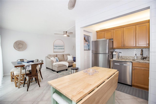 kitchen featuring tasteful backsplash, ceiling fan, sink, appliances with stainless steel finishes, and light tile patterned floors