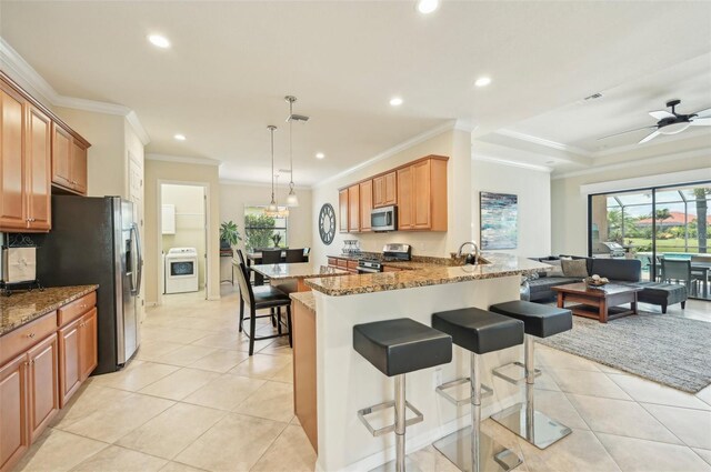 kitchen featuring ceiling fan, crown molding, a kitchen bar, appliances with stainless steel finishes, and kitchen peninsula