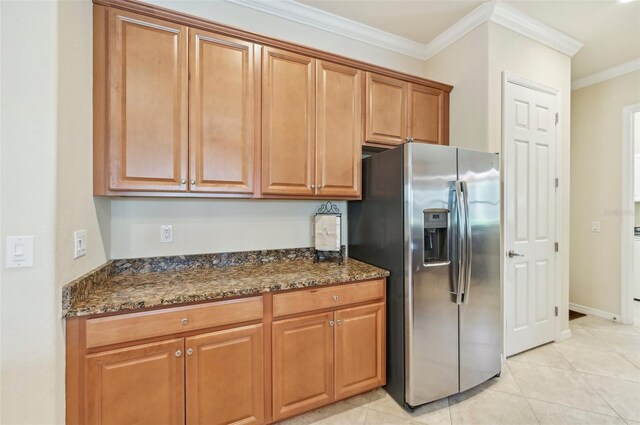 kitchen featuring dark stone counters, light tile patterned flooring, stainless steel refrigerator with ice dispenser, and crown molding