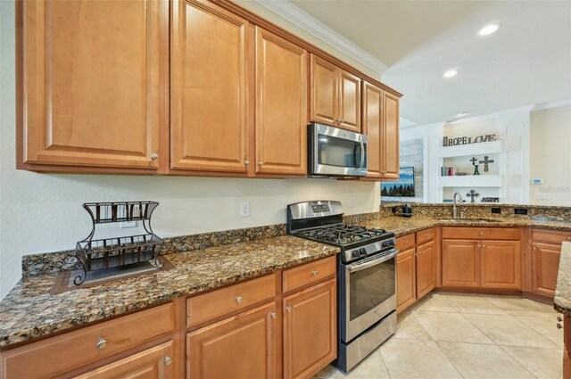 kitchen with dark stone countertops, sink, stainless steel appliances, and light tile patterned floors