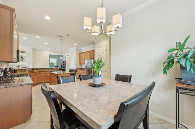 tiled dining room with crown molding, sink, and a chandelier