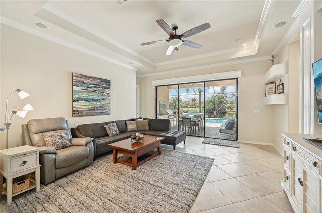 living room featuring ceiling fan, ornamental molding, light tile patterned floors, and a tray ceiling