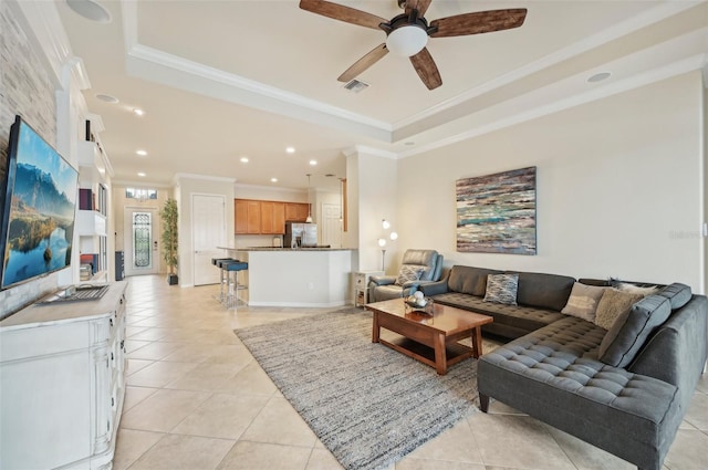 living room featuring light tile patterned flooring, ceiling fan, a raised ceiling, and crown molding