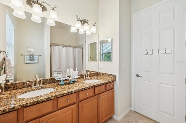 bathroom with a notable chandelier, double sink vanity, and tile patterned flooring