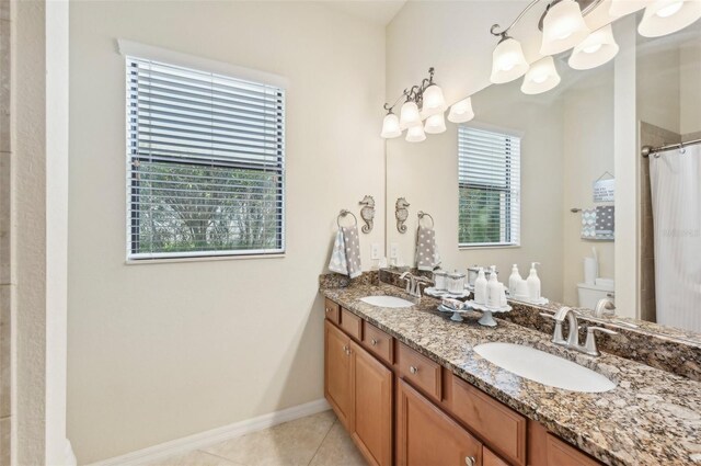 bathroom featuring toilet, tile patterned flooring, and double vanity