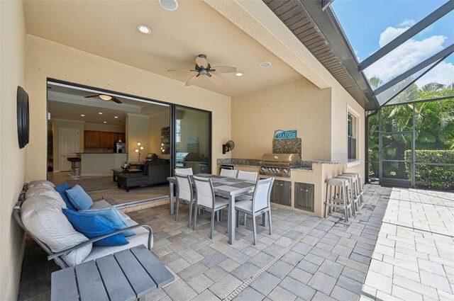 view of patio featuring ceiling fan, a lanai, exterior bar, area for grilling, and an outdoor kitchen