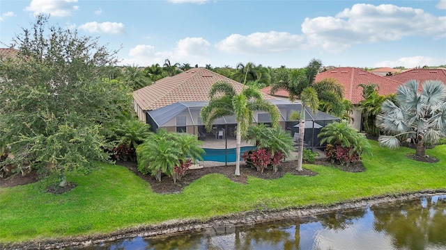 rear view of house featuring a lanai, a water view, and a yard