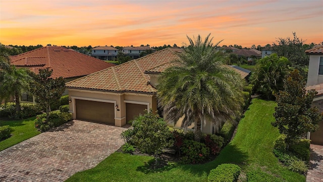 mediterranean / spanish-style house featuring a garage and a lawn