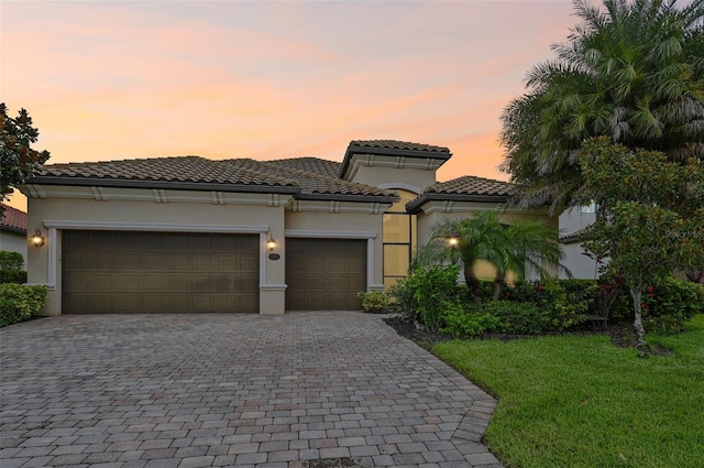 13215 Ramblewood Trl, Bradenton, FL 34211 - mediterranean / spanish-style home featuring stucco siding, decorative driveway, an attached garage, a tiled roof, and a lawn