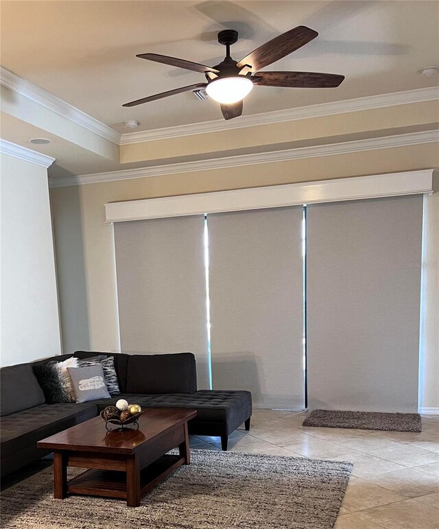 tiled living room with a tray ceiling, ornamental molding, and ceiling fan