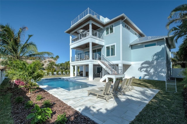 back of property with a balcony, a lawn, and a patio area