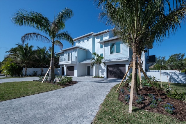 view of front of property featuring a balcony, a garage, and a front yard