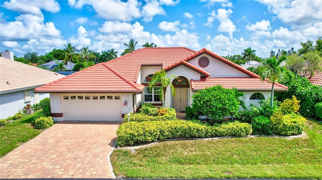 mediterranean / spanish-style house with a garage and a front lawn