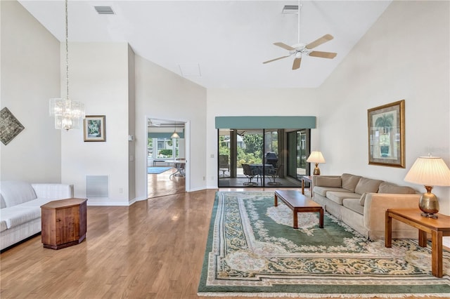 living room featuring ceiling fan with notable chandelier, hardwood / wood-style floors, and high vaulted ceiling