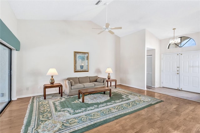 living room featuring hardwood / wood-style flooring, ceiling fan with notable chandelier, and high vaulted ceiling