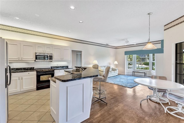 kitchen with pendant lighting, white cabinetry, stainless steel appliances, and a breakfast bar