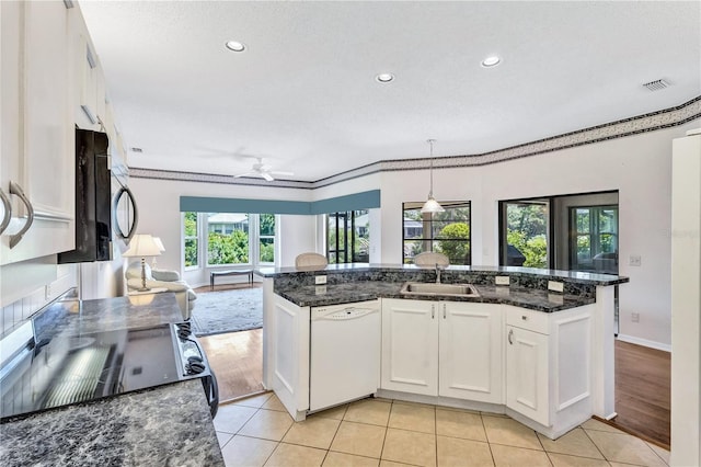 kitchen featuring sink, dishwasher, white cabinetry, dark stone countertops, and decorative light fixtures