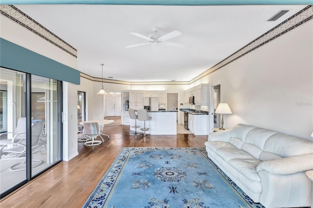 living room featuring crown molding, dark wood-type flooring, and ceiling fan