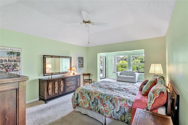 bedroom featuring ceiling fan, lofted ceiling, light colored carpet, and a textured ceiling