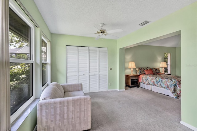 carpeted bedroom with a textured ceiling, ceiling fan, and a closet