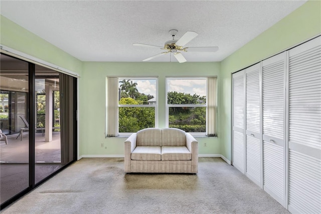 living area with ceiling fan and a textured ceiling