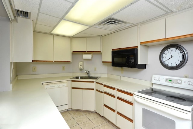 kitchen with light tile patterned flooring, sink, white cabinetry, white appliances, and a drop ceiling