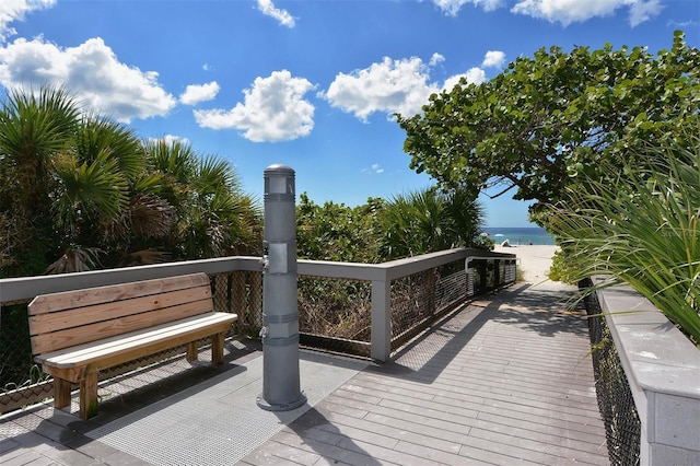 wooden deck featuring a view of the beach and a water view